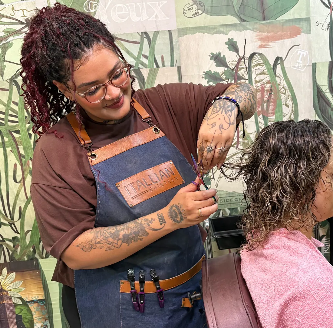 Anne Caroline cortando cabelo cacheado de uma cliente no salão Awá Lab em São Carlos
