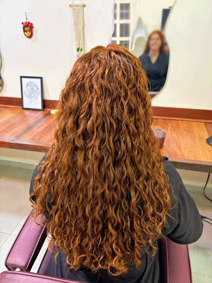 Cabelo longo cacheado em tom ruivo acobreado, visto de trás, no salão Awá Lab